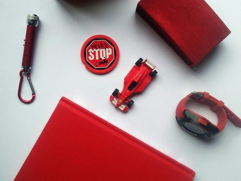 Objets variés rouges : voiture miniature, carnet, badge, bracelet et clé. Sécurité voiture